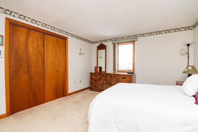 bedroom featuring baseboards, a closet, and light colored carpet