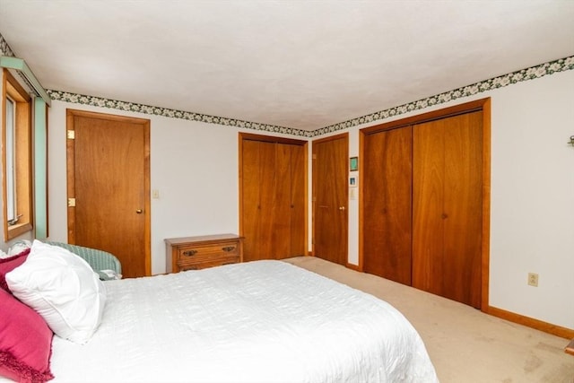 bedroom with carpet floors, baseboards, and multiple closets