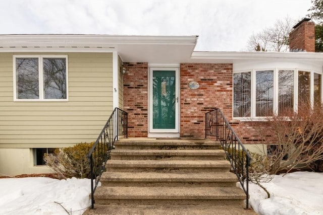 entrance to property with a chimney and brick siding