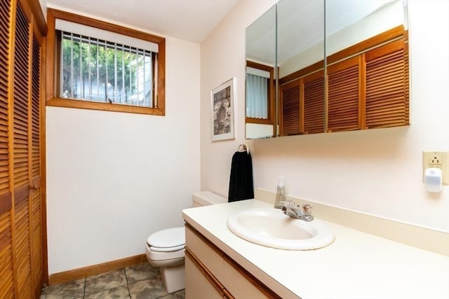 bathroom with baseboards, toilet, tile patterned floors, vanity, and a closet