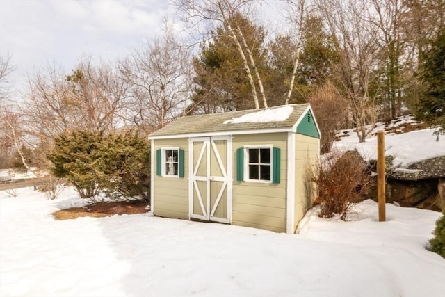 snow covered structure featuring a shed and an outbuilding