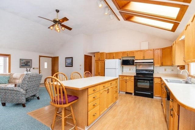 kitchen with open floor plan, black range with electric stovetop, freestanding refrigerator, light countertops, and a sink