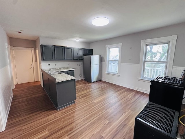 14 Gage St, Worcester, MA 01605 - kitchen with freestanding refrigerator, light countertops, light wood finished floors, and wainscoting