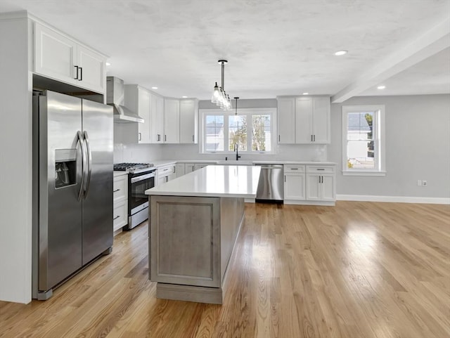 kitchen featuring plenty of natural light, stainless steel appliances, wall chimney exhaust hood, and light countertops