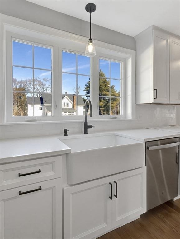 kitchen with dark wood-style flooring, a sink, decorative backsplash, white cabinets, and stainless steel dishwasher