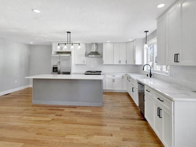 kitchen featuring light wood-style flooring, stainless steel appliances, wall chimney exhaust hood, and a sink