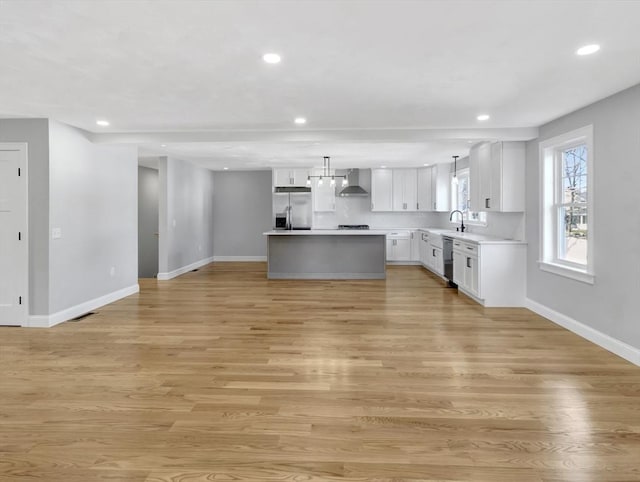 kitchen featuring recessed lighting, light wood-style flooring, appliances with stainless steel finishes, and wall chimney exhaust hood