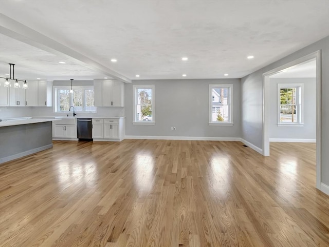 unfurnished living room with recessed lighting, baseboards, a sink, and light wood finished floors