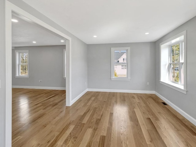 unfurnished room with a wealth of natural light, light wood-style flooring, and baseboards