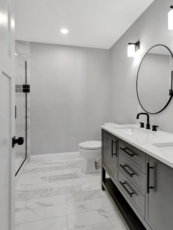 full bath featuring baseboards, a stall shower, a sink, toilet, and marble finish floor