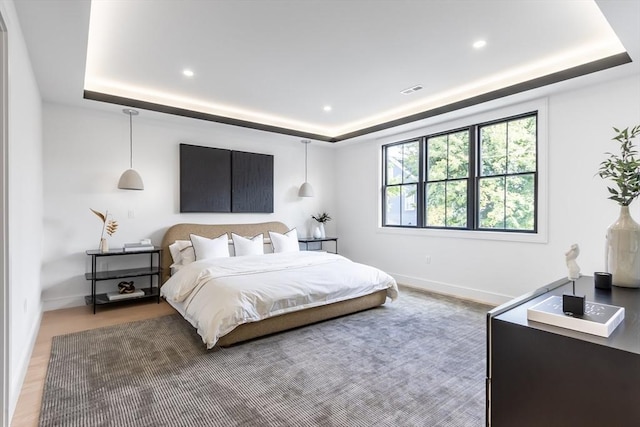 bedroom with a raised ceiling and dark wood-type flooring