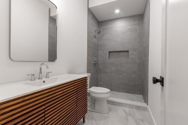 bathroom featuring toilet, tiled shower, and vanity