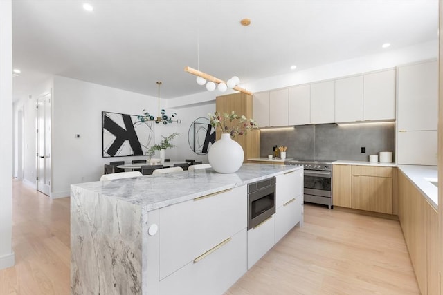 kitchen featuring decorative light fixtures, white cabinets, stainless steel appliances, and a kitchen island