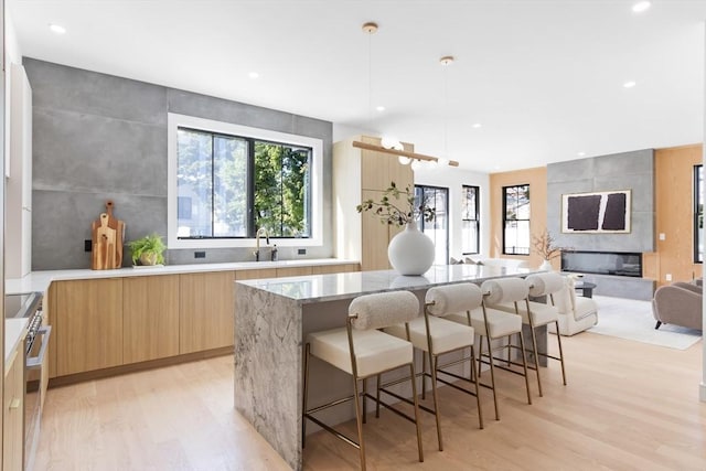 kitchen featuring high end stove, a fireplace, light stone countertops, pendant lighting, and a center island