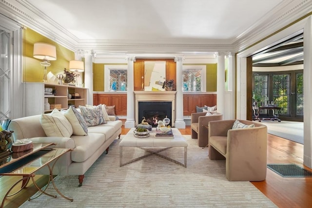 living area featuring a lit fireplace, crown molding, a wainscoted wall, wood finished floors, and a decorative wall