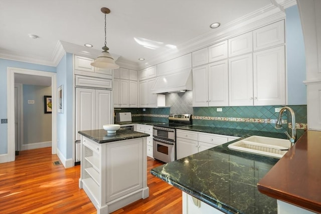 kitchen featuring range with two ovens, premium range hood, a sink, white cabinets, and ornamental molding