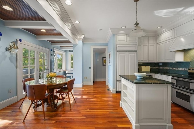 kitchen with double oven range, baseboards, dark countertops, white cabinetry, and crown molding