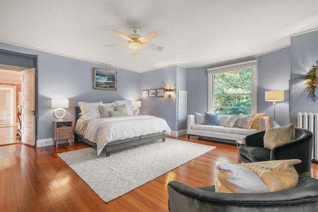 bedroom featuring radiator, hardwood / wood-style flooring, ceiling fan, and baseboards