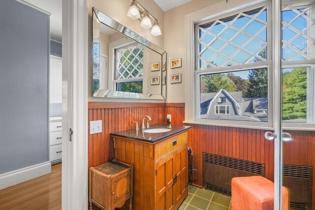 indoor wet bar featuring radiator heating unit, wainscoting, and wooden walls