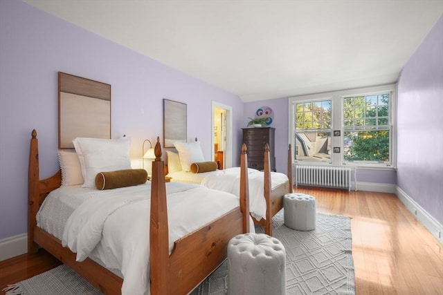 bedroom featuring radiator, wood finished floors, and baseboards