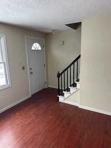 entrance foyer featuring baseboards, a textured ceiling, wood finished floors, and stairs