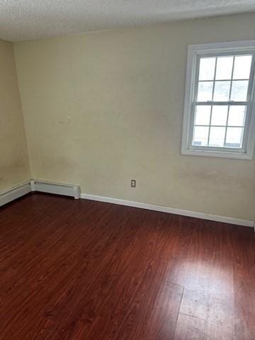 spare room with dark wood-style floors, baseboards, and a textured ceiling