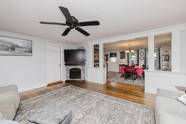 700 S Main St, Bellingham, MA 02019 - living area featuring wood finished floors, a chandelier, ceiling fan, baseboards, and a stone fireplace