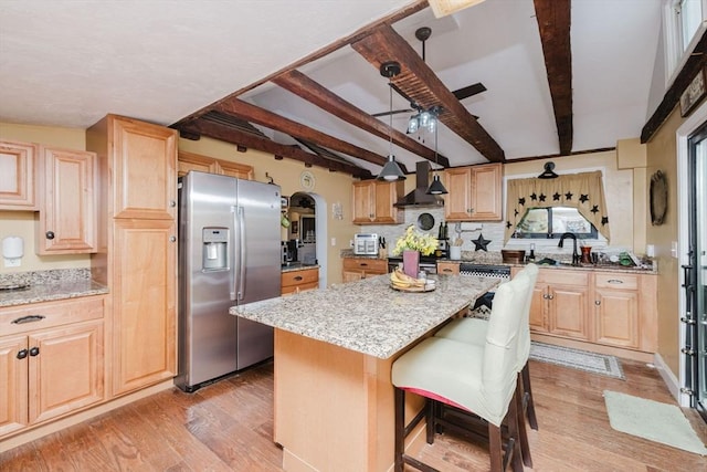 700 S Main St, Bellingham, MA 02019 - kitchen featuring stainless steel fridge with ice dispenser, wall chimney range hood, light wood-style floors, light stone counters, and beam ceiling