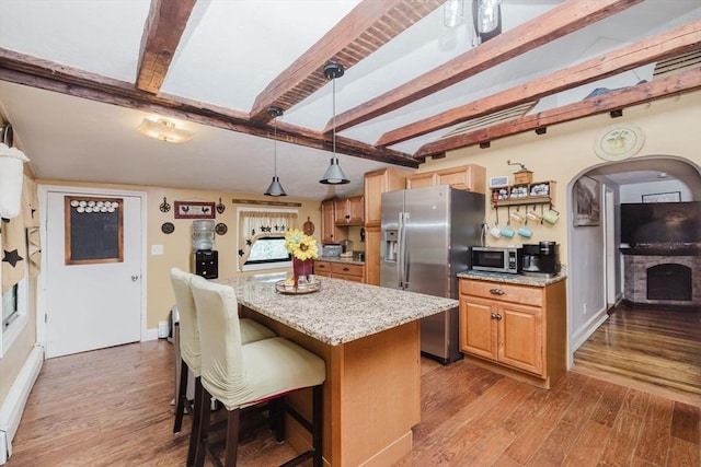 700 S Main St, Bellingham, MA 02019 - kitchen featuring stainless steel appliances, a center island, light stone countertops, wood finished floors, and a kitchen bar