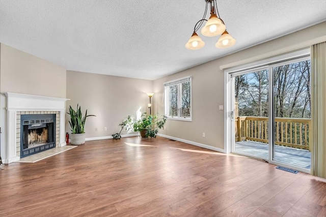 unfurnished living room featuring a tile fireplace, wood-type flooring, and a textured ceiling