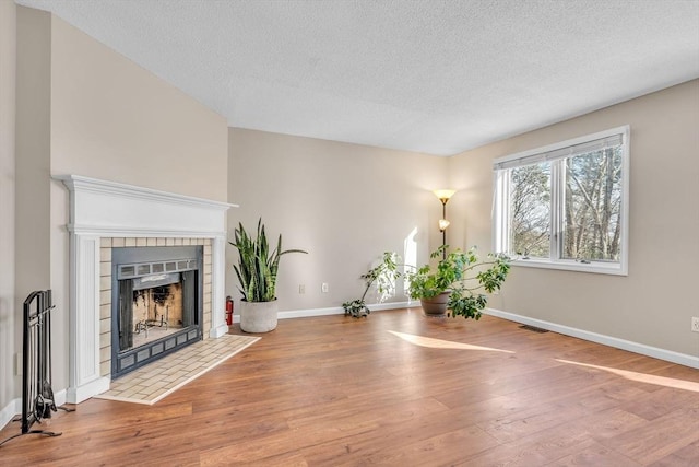 unfurnished living room featuring hardwood / wood-style floors, a textured ceiling, and a fireplace