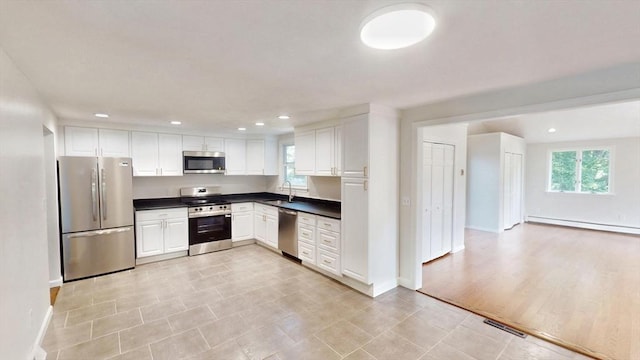 12 Sandra Ave, Burlington, MA 01803 - kitchen with stainless steel appliances, dark countertops, white cabinetry, baseboard heating, and recessed lighting