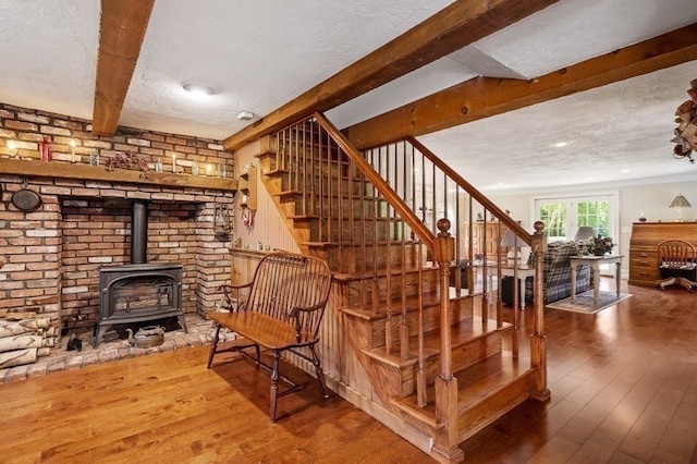 stairway featuring wood-type flooring, a wood stove, and a textured ceiling