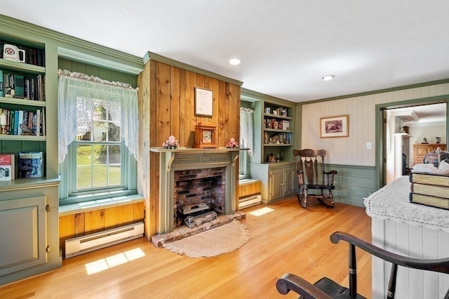 interior space featuring ornamental molding, light hardwood / wood-style flooring, a baseboard heating unit, and built in shelves