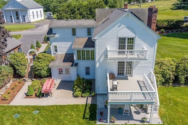 rear view of property with a patio, a lawn, and a balcony