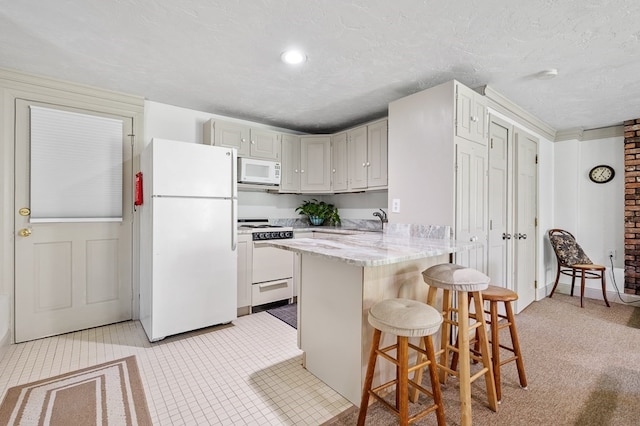 kitchen featuring a breakfast bar area, kitchen peninsula, white cabinets, a textured ceiling, and white appliances