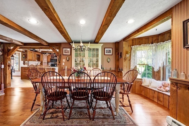 dining area with light hardwood / wood-style floors, beamed ceiling, a baseboard radiator, and a chandelier