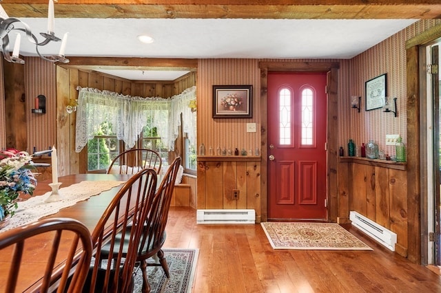 entrance foyer featuring a notable chandelier, wood walls, baseboard heating, and hardwood / wood-style floors