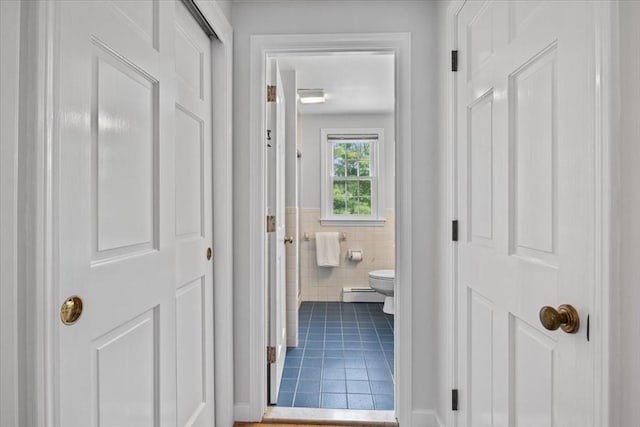 24 Stagecoach, Medfield, MA 02052 - hallway with a baseboard radiator, tile patterned floors, tile walls, and a wainscoted wall
