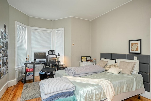 bedroom featuring crown molding, wood finished floors, and baseboards