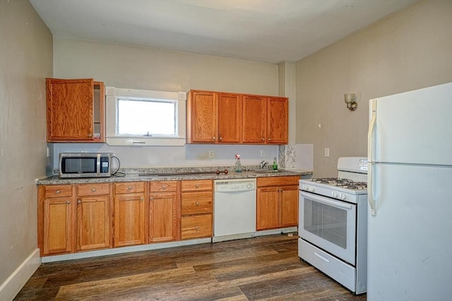 kitchen featuring white appliances, dark wood finished floors, a sink, light countertops, and brown cabinets