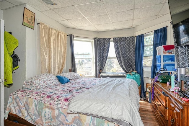 bedroom with a drop ceiling, visible vents, and wood finished floors