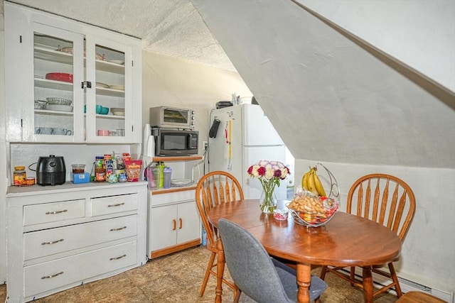 dining room with lofted ceiling, baseboard heating, and a textured ceiling