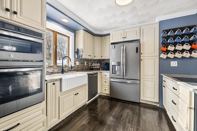 kitchen featuring sink, appliances with stainless steel finishes, dark hardwood / wood-style floors, tasteful backsplash, and cream cabinets