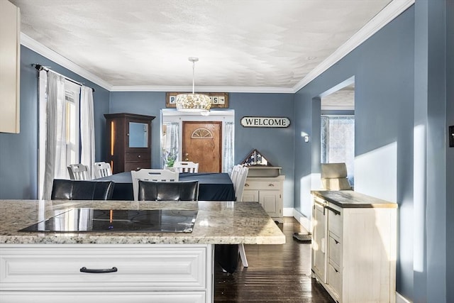 kitchen with hanging light fixtures, plenty of natural light, light stone counters, and black electric cooktop