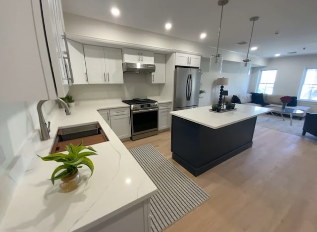 kitchen featuring a kitchen island, light hardwood / wood-style flooring, sink, pendant lighting, and stainless steel appliances