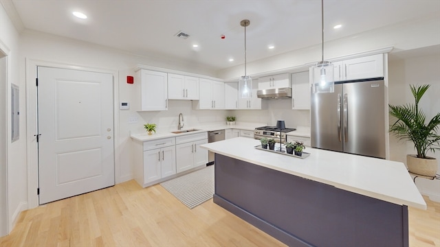 kitchen featuring appliances with stainless steel finishes, a center island, white cabinetry, light hardwood / wood-style floors, and decorative light fixtures