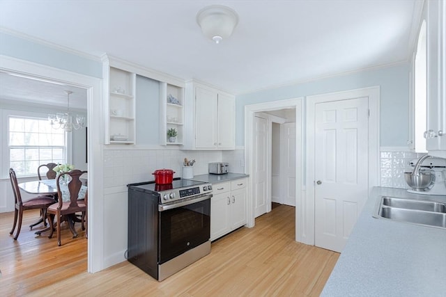 kitchen with sink, white cabinetry, hanging light fixtures, stainless steel electric stove, and light hardwood / wood-style floors