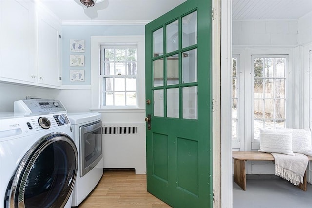 laundry room featuring radiator, cabinets, washing machine and clothes dryer, light hardwood / wood-style floors, and crown molding