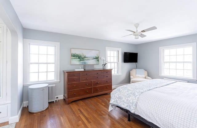 bedroom with ceiling fan, radiator heating unit, and hardwood / wood-style floors